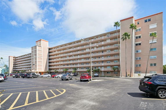 Front view of a multi-story apartment building with a parking area.