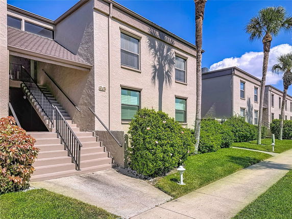 Front view of a two-story building with exterior stairs and landscaped greenery.