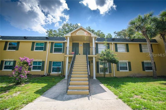 Front view of a two-story yellow building with green shutters and central staircase