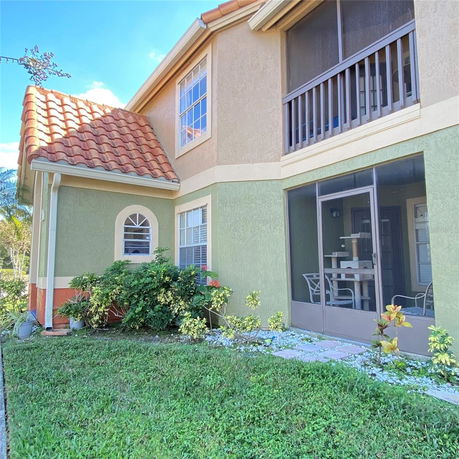 Front view of a two-story house with screened patio and terracotta roof tiles.