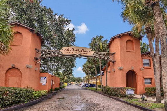Front view of a gated residential complex entrance with two orange buildings on either side and a sign overhead.