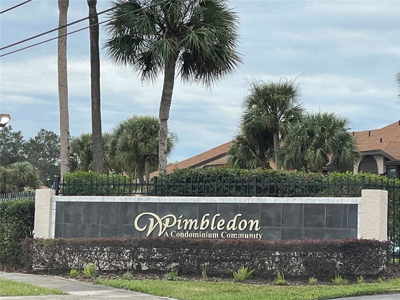 View of Wimbledon Condominium Community signage with surrounding palm trees.