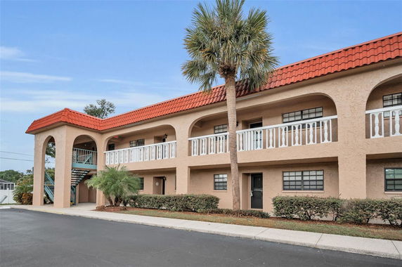 Front view of a two-story building with arches and a red tiled roof.