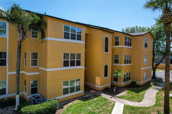Front view of a multi-story yellow apartment building with multiple windows and an arched entrance.