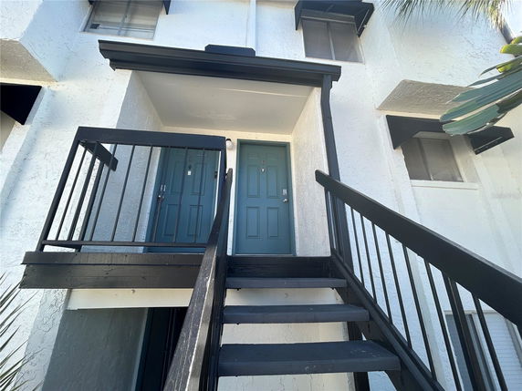 Front view of a building entrance with stairs leading up to a double door.