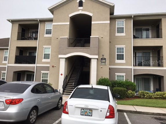 Front view of a multi-story apartment building with parking spaces.