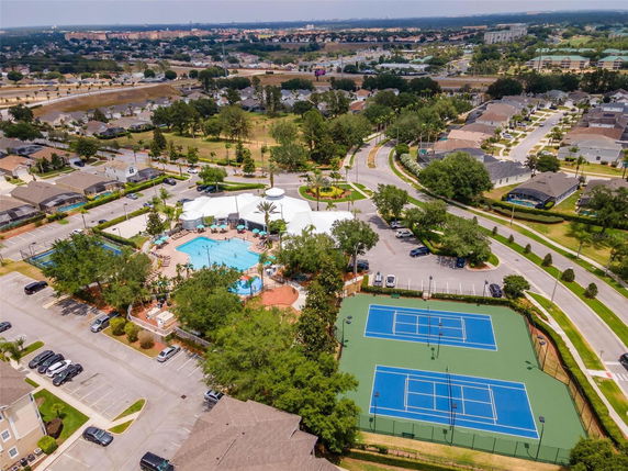 Aerial view of a neighborhood with a swimming pool, tennis courts, and surrounding residential area.