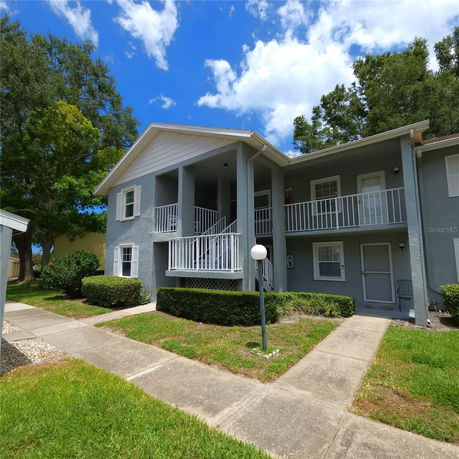 Front view of a two-story residential building with balconies and a pathway leading to the entrance.