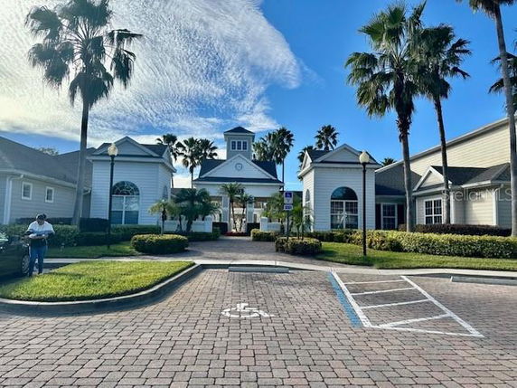 Front view of a large building with multiple peaked roofs and a central tower, surrounded by palm trees.