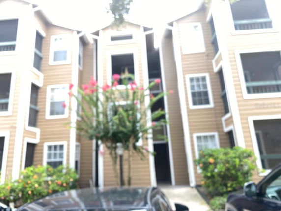 Front view of a multi-story apartment building with wood siding and several windows.