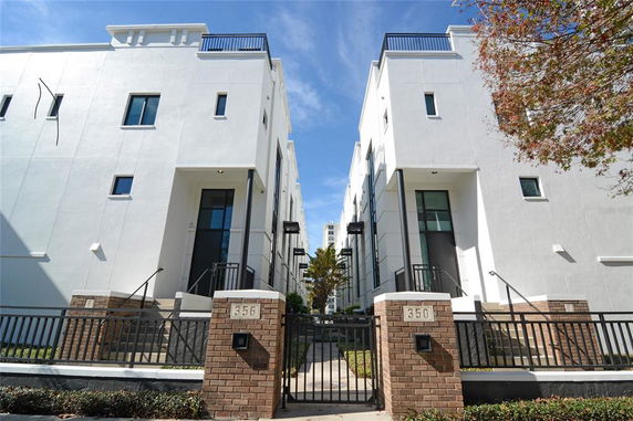 Front view of a modern multi-story building with brick columns and gated entrances.