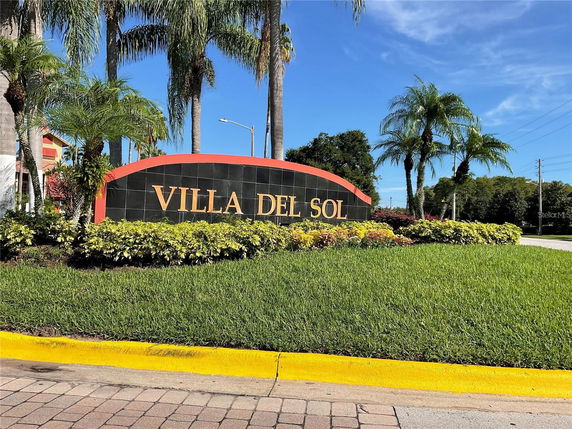 Signage displaying the name 'Villa Del Sol' surrounded by landscaping and palm trees.