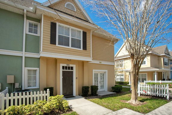 Front view of a two-story house with a front porch and picket fence.