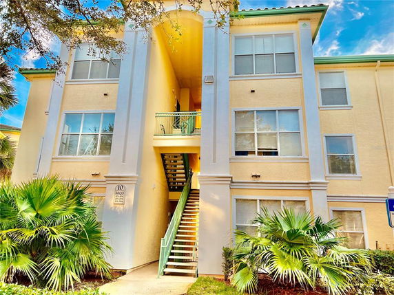 Front view of a multi-story building with an exterior staircase and large windows.