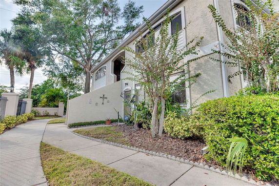Front view of a two-story house with a walkway and surrounding plants.