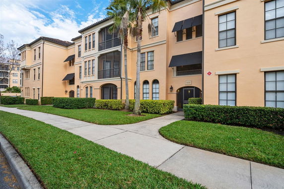 Front view of a multi-story apartment building with balconies and a stucco exterior.