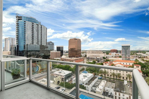 Panoramic view of a cityscape from a balcony, showcasing high-rise buildings and clear skies.
