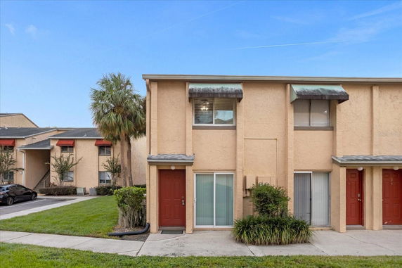 Front view of a two-story townhouse building with red doors and beige exterior.
