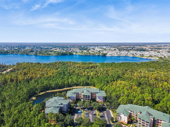 Panoramic view of buildings surrounded by trees and a lake in the background.