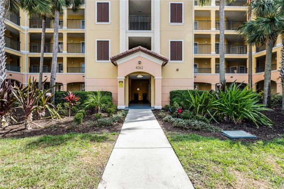 Front view of a multi-story building with balconies and landscaped entrance.