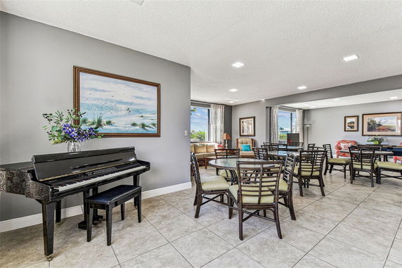 Interior view of a clubhouse with tables, chairs, and a piano.