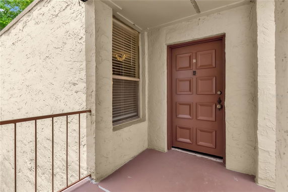 Front view of a building entrance with a brown door and textured walls.