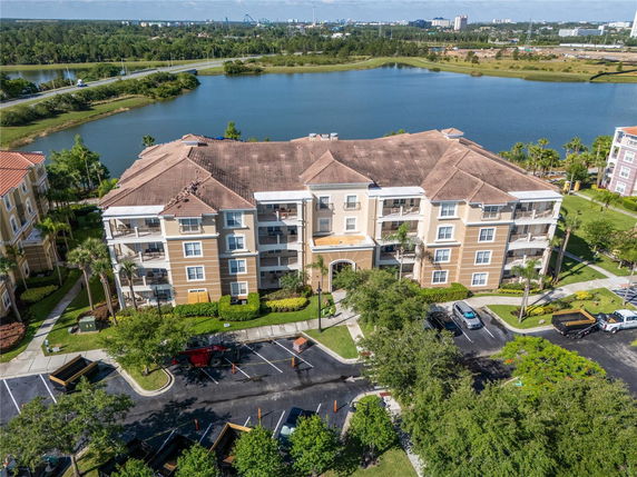 Front view of a multi-story residential building with balconies and parking in front.
