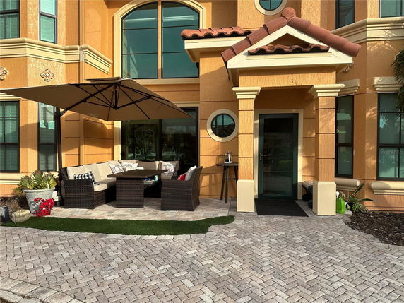 Front view of a house with a patio and umbrella, brick walkway, and yellow exterior.