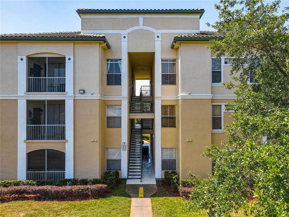 Front view of a multi-story apartment building with balconies and a central entrance.