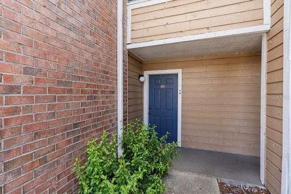 Entryway of a building with a blue door and brick siding.