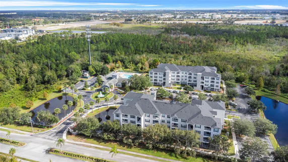 Aerial view of apartment complex with multiple buildings and surrounding natural landscape.
