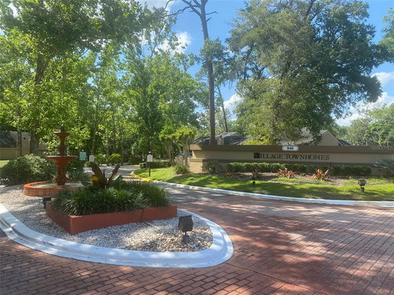 Entrance view of Village Townhomes with a landscaped garden and a fountain.