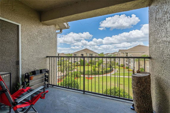 Balcony view showing apartment buildings and garden area.