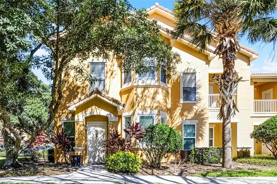 Front view of a two-story yellow house with white trim and a prominent entrance.