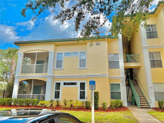 Front view of a two-story apartment building with a staircase and balconies.