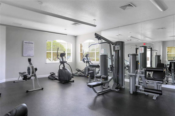 Indoor gym area with various fitness equipment and mirrors on the wall.