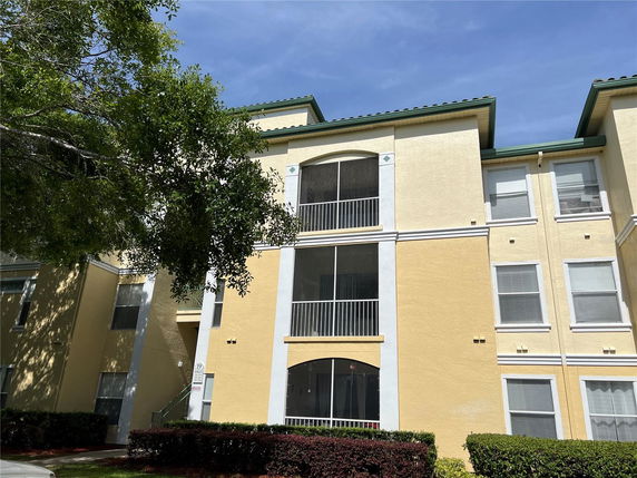 Front view of a multi-story apartment building with yellow walls and green roof accents.