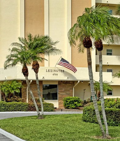 Front view of a building with an American flag and palm trees.
