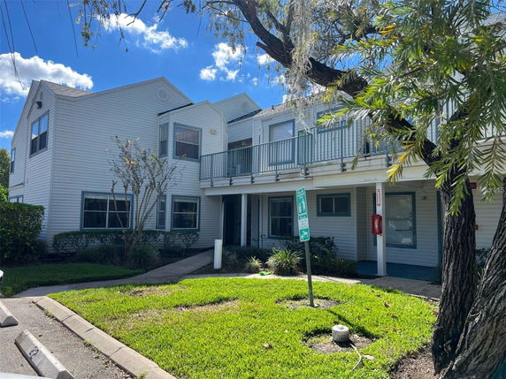 Front view of a two-story building with white siding and a balcony.