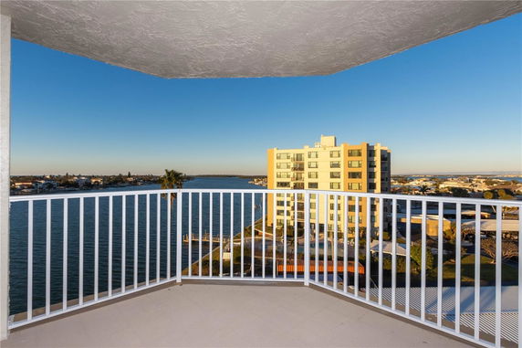 View from a balcony with a railing overlooking water and a distant building.