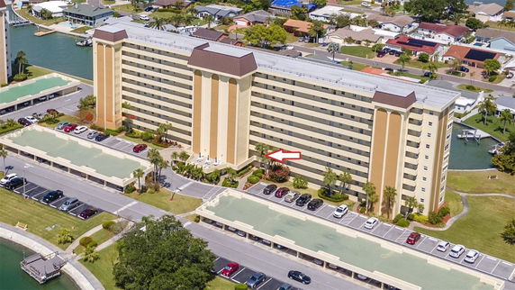 Front view of a multi-story building with parking spaces and nearby waterway.