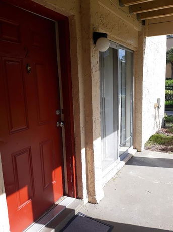 Front view of a building entrance with a red door and adjacent sliding glass doors.
