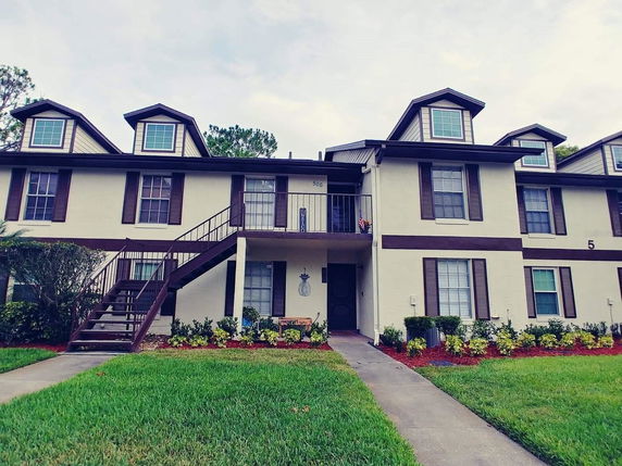 Front view of a two-story building with dormer windows and an external staircase.