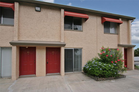 Front view of a two-story building with red doors and window awnings.