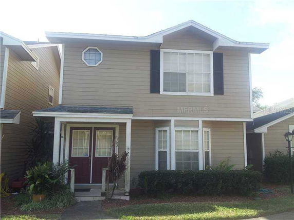 Front view of a two-story house with a porch and dark window shutters.