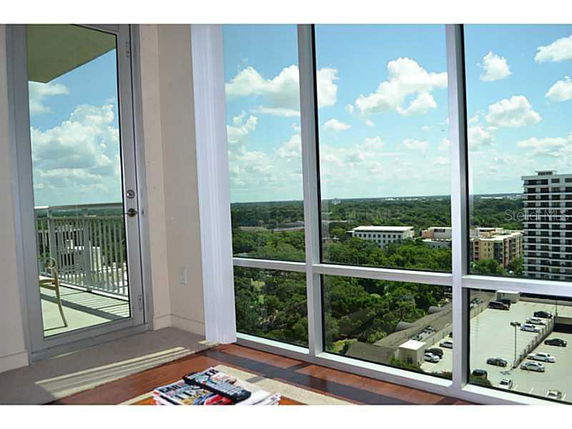 Panoramic view from a high-rise building showing surrounding areas with trees and other buildings.