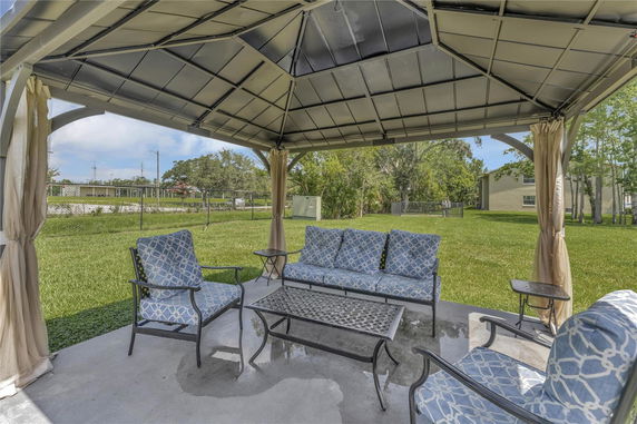 Outdoor patio area with a metal gazebo and outdoor furniture.