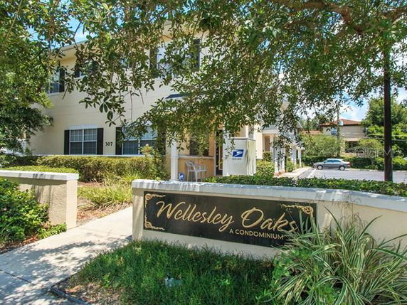 Front view of a condominium building with a sign reading 'Wellesley Oaks.'
