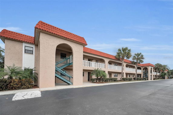 Front view of a two-story building with red-tiled roof and outdoor staircases.