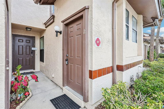Front view of a house entry with brown doors and small garden.